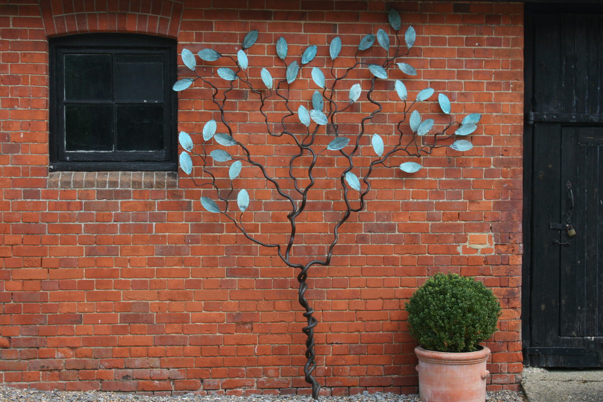 Espalier tree wall climbing sculpture with verdigris leaves by Mark Reed garden sculpture